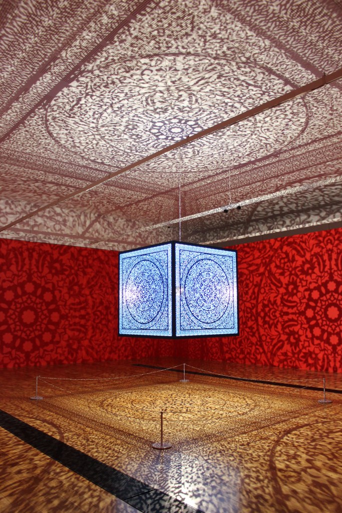 large, laser-cut steel cube suspended from the gallery ceiling fills the space with elaborate floor-to-ceiling shadows
